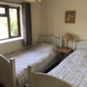 The second bedroom has twin beds, a bed side table and a large chest of drawers